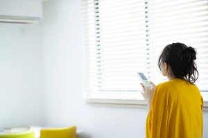 エアコンの操作をしている女性の写真