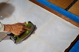 アイロンで障子の張り替えを行っている写真
