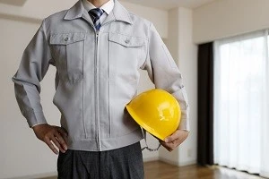 窓の前に立つ修理事業者の男性の写真